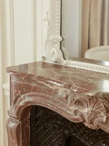 Klassischer Marmorkamin mit kunstvollem Spiegel in einem elegantem Raum