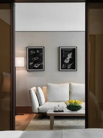 Modernes Schlafzimmer mit Blick auf eine Sofa-Sitzecke durch eine Glastür.