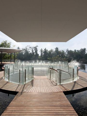 Runder Infinity Pool mit Glasumzäunung und Dampfeffekten im Freien