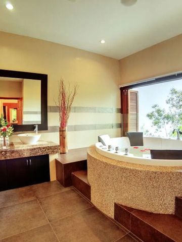 Großes Badezimmer mit freistehender Badewanne und Blick ins Grüne