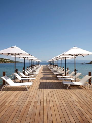 Langer Steg mit Liegestühlen und Sonnenschirmen ins Meer