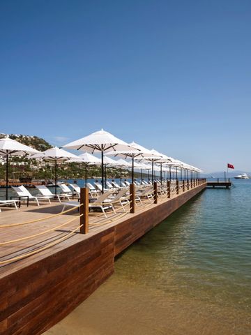 Eleganter Steg mit Sonnenliegen am ruhigen Meer.