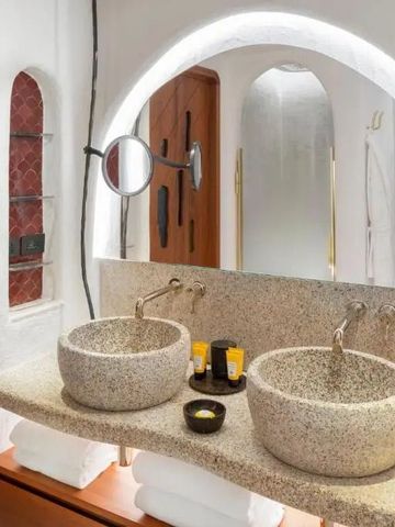 Badezimmer mit runden Waschbecken und beleuchtetem Spiegel