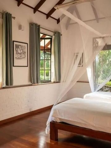 Zweibettzimmer mit Moskitonetz und Blick in den Garten