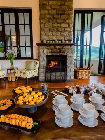 Gemütliche Lounge mit Kamin im Hotel, umgeben von Fenstern mit Blick auf die Landschaft