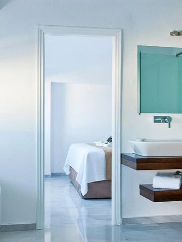 Modernes Badezimmer mit freistehender Wanne, großem Spiegel und Zugang zum Schlafbereich.