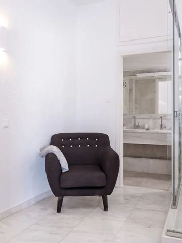 Helles Zimmer mit komfortablem Sessel und Dusche. Stilvolle weiße Einrichtung.