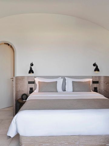 Helles Schlafzimmer mit weißer Bettwäsche und eleganter Einrichtung.