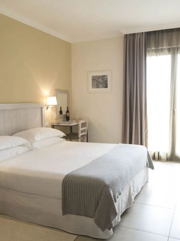 Helles Hotelzimmer mit Doppelbett, zwei Nachttischen und einem Schreibtisch