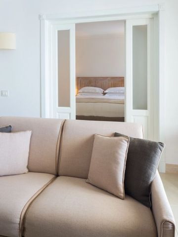 Elegantes Zimmer mit Sofa, Kissen und Schiebetür zum Bettbereich im Canne Bianche Lifestyle Hotel.