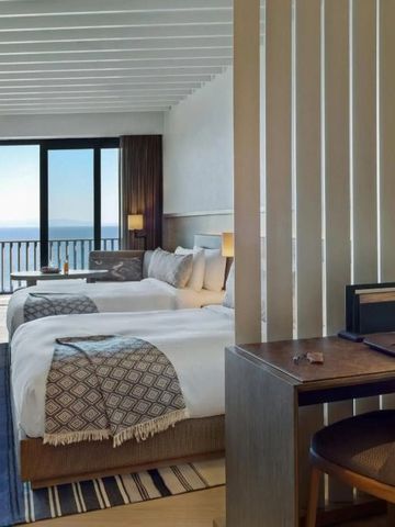 Helles Hotelzimmer mit zwei Einzelbetten und Meerblick vom Balkon