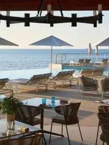 Terrasse mit Liegestühlen und Sonnenschirmen am Pool mit Meerblick