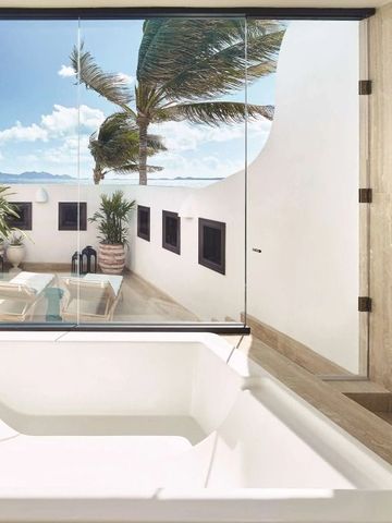 Badezimmer mit Badewanne und großer Fensterfront mit Palmenblick