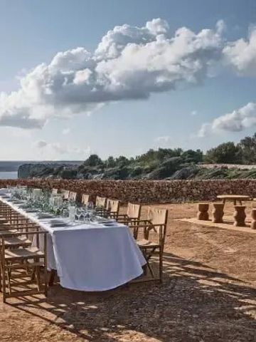 Eleganter langer Tisch für ein Outdoor-Dinner mit Meerblick