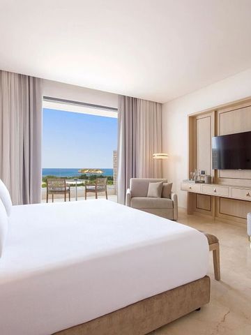 Helles Hotelzimmer mit komfortablem Bett und Blick aufs Meer