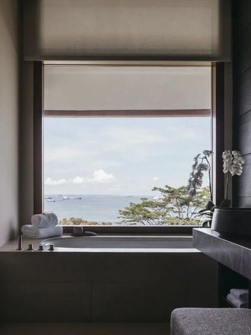 Luxuriöses Badezimmer mit Meerblick durch großes Fenster