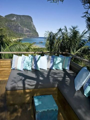 Sitzbereich mit Kissen, umgeben von Palmen und Meerblick