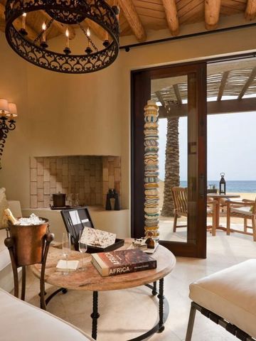 Elegantes Wohnzimmer mit Kamin und Meerblick durch große Glastüren.