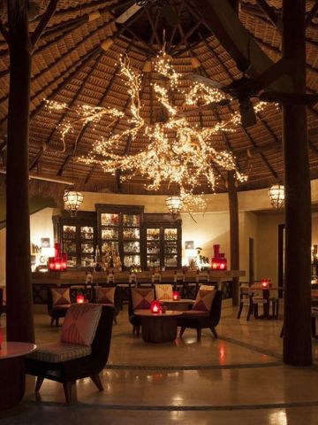 Elegante Hotel-Lounge mit beleuchteter Dekoration unter einem Strohdach.