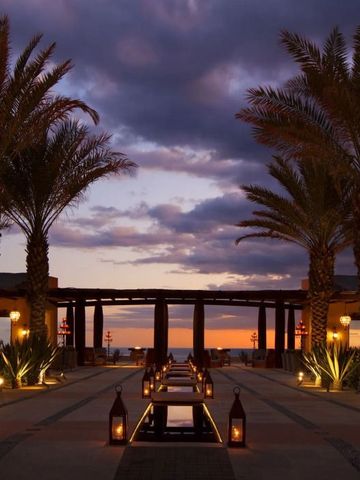 Hotelpromenade mit Palmen bei Sonnenuntergang, elegant beleuchtet.