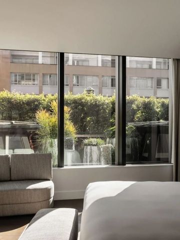 Helles Zimmer mit großen Fenstern und Blick auf eine grüne Terrasse.