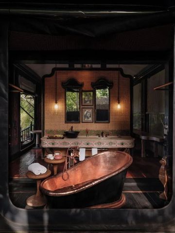 Luxuriöses Badezimmer mit freistehender Kupferbadewanne und üppiger Dekoration