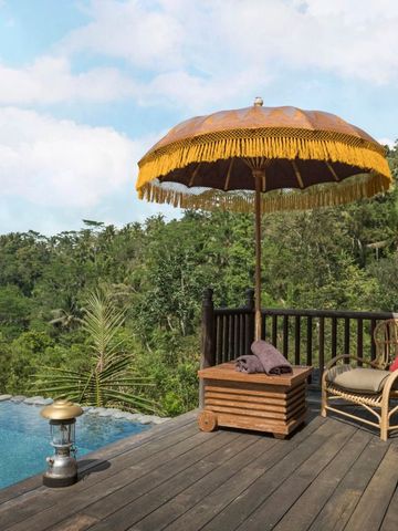 Holzterrasse mit Pool und Sonnenschirm in tropischer Waldlandschaft