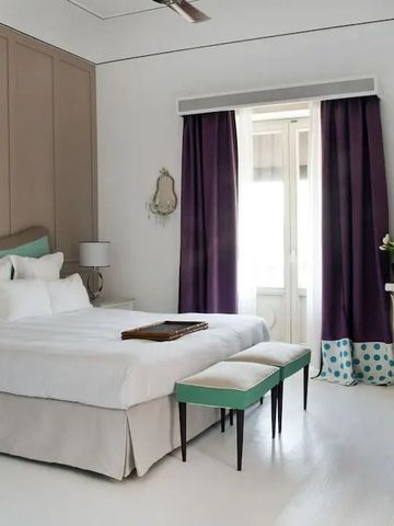 Helles Zimmer mit Doppelbett, lila Vorhängen und stilvollen Möbeln im Capri Tiberio Palace