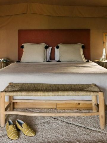 Gemütliches Zeltzimmer mit Doppelbett und Holzbank im Caravan Agafay