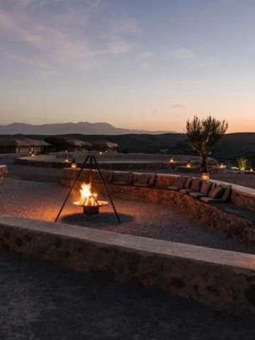 Sitzbereich im Freien mit Feuerschale in der Wüste bei Sonnenuntergang