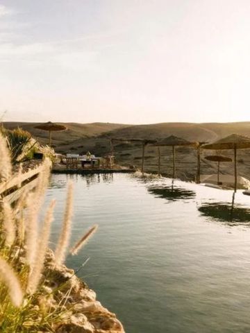 Infinity-Pool mit Blick auf die Wüstenlandschaft bei Sonnenuntergang