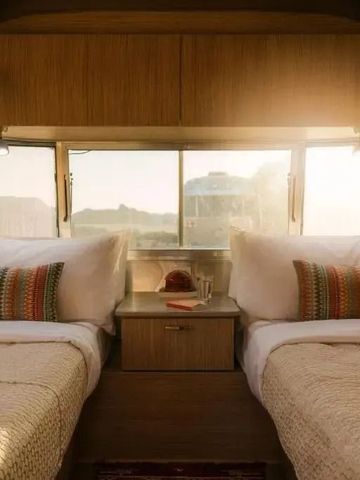 Zwei komfortable Einzelbetten mit Holzvertäfelung in einem Wohnwagen