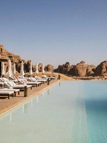 Infinity-Pool mit Sonnenliegen und Blick auf felsige Landschaft