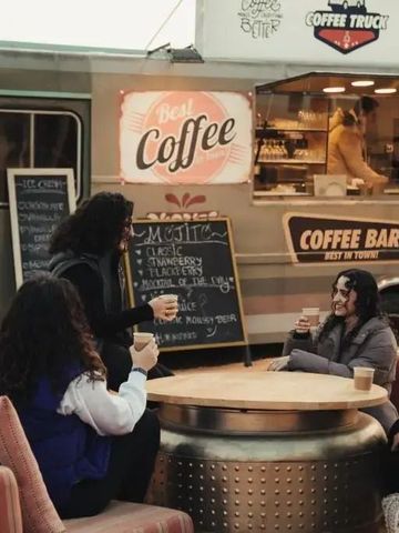 Leute genießen Kaffee neben einem stilvollen Coffee-Truck im Freien.