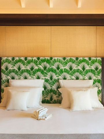 Helles Zimmer mit großem Bett und grünem Blätterdekor am Kopfteil