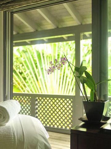 Helles Zimmer mit Balkonblick auf üppiges grünes Laub und Orchideen