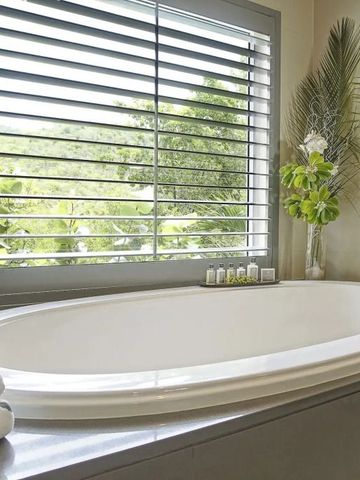 Moderner Badewannenbereich mit Blick auf grüne Natur durch große Fenster