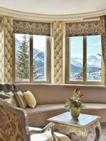 Luxuriöses Wohnzimmer mit Panoramablick auf verschneite Berge und edlen Möbeln