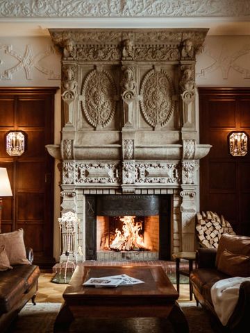 Gemütliche Lounge mit prunkvollem Kamin und edler Holzvertäfelung