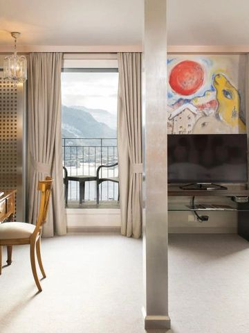 Helles Hotelzimmer mit Schreibtisch und Kunstwerk an der Wand vor Bergkulisse