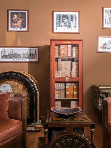 Gemütliche Lounge mit Sesseln, dekorativen Bildern und einem Zigarrenschrank