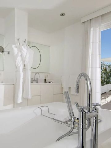 Elegantes Badezimmer mit Badewanne und Terrasse mit Meerblick