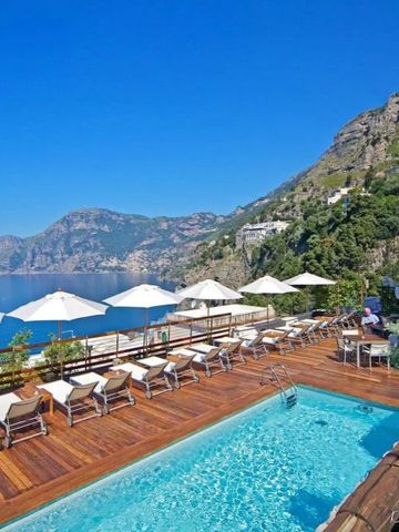 Infinity Pool mit Blick auf die Amalfiküste und Liegestühle unter Sonnenschirmen