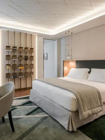 Komfortables Doppelbett in einem stilvoll eingerichteten Hotelzimmer mit Akzentbeleuchtung.