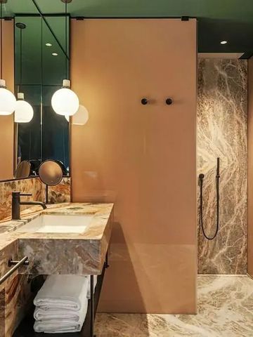 Luxuriöses Badezimmer mit Marmorwänden und modernen Leuchten