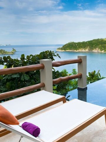 Zwei Liegestühle am Infinity Pool mit Blick auf das Meer und Inseln