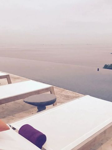 Elegante Liegestühle mit Blick auf Infinity-Pool und Meer bei Sonnenuntergang