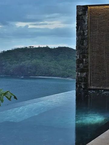 Infinity-Pool mit Wasserwand und Blick auf bewaldete Hügel und Meer