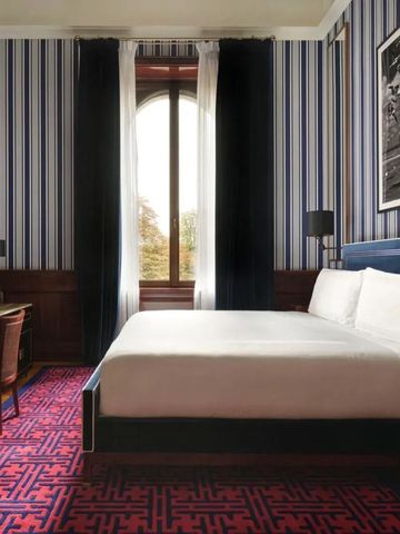 Elegantes Hotelzimmer mit gestreiften Tapeten und großem Fenster