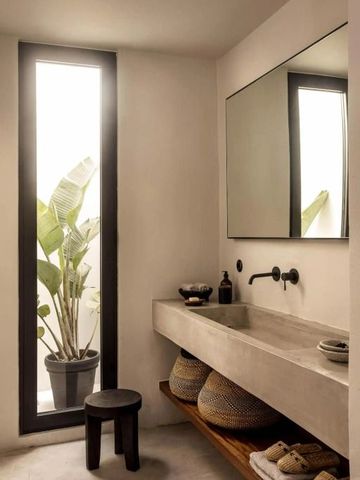 Minimalistisches Badezimmer mit tropischen Pflanzen und großem Spiegel